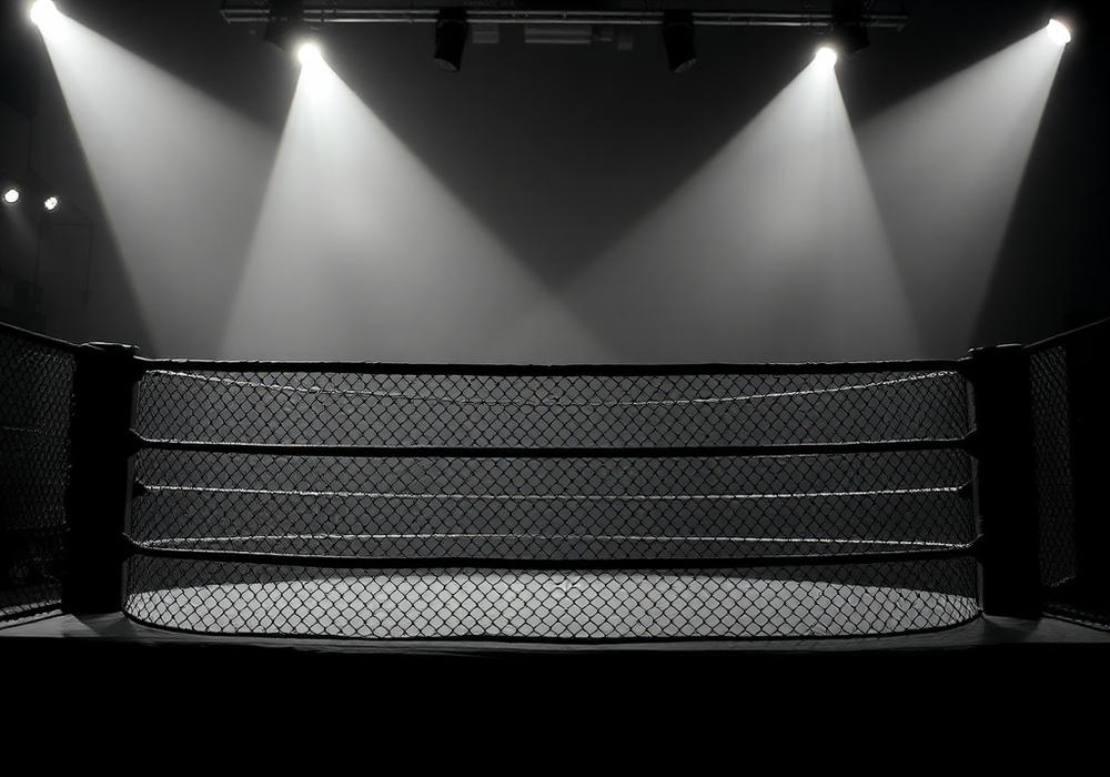 Cage MMA grillagée éclairée dans une salle sombre